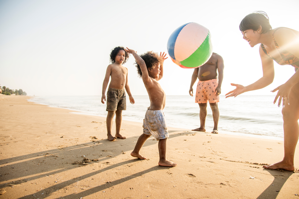 family playing on the beach during a beach family photoshoot with a beach ball
